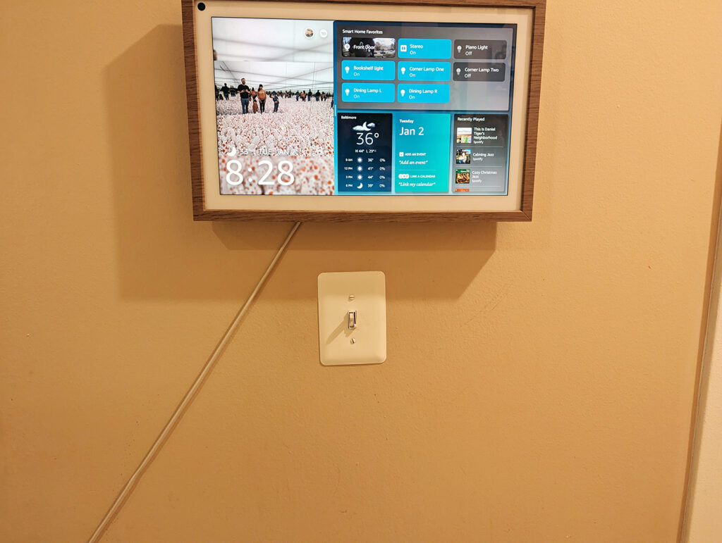 Photo of Echo Show 15 mounted on the wall with wire from power supply showing.